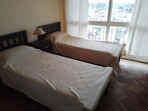 two beds in a hotel room with a window at Céntrico y confortable in Concepción del Uruguay