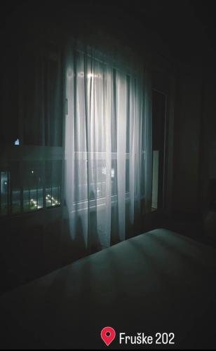 a dark room with a window with a curtain at Fruške 202 studio apartman in Vrdnik