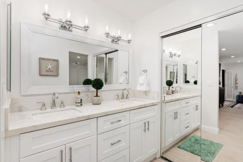 a white bathroom with two sinks and two mirrors at Solana Escape - SUR44 in Solana Beach