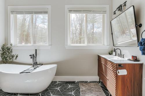 a bathroom with a tub and two sinks and two windows at Two Forest Cabins,Decks,Fire Pit,Hot Tubs,GameRoom in Berkeley Springs