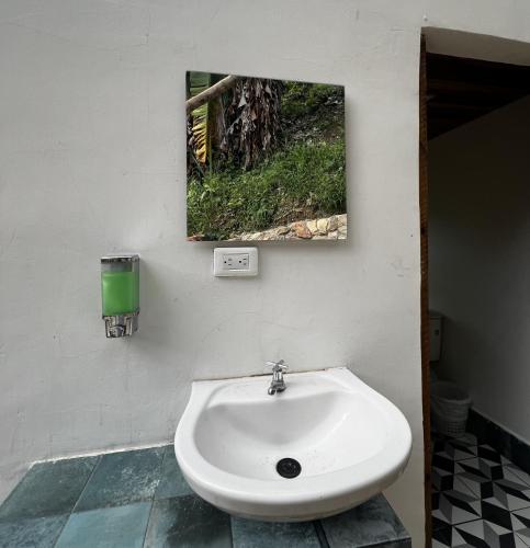 a white sink in a bathroom with a picture on the wall at Puerto Alto Hostel in Santa Marta