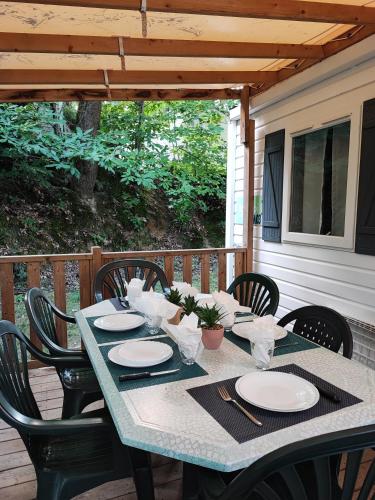 - une table avec des chaises et des assiettes sur la terrasse dans l'établissement Tiny Sweet Home, à Saint-Chéron