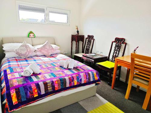 基督城LilyのHome Elegant Retreat near Riccarton Mall的一间卧室，配有一张床、一张桌子和几把椅子