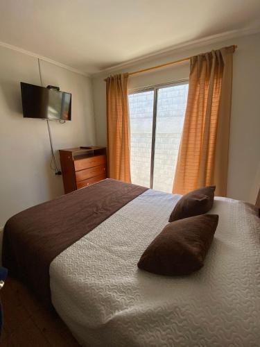 a bedroom with a bed with two pillows and a window at Hotel & Cabañas El Mirador Caldera in Caldera