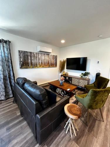 a living room with a black leather couch and chairs at Brand New Loft in the Heart of Downtown Bozeman in Bozeman