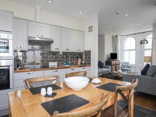 a kitchen and dining room with a wooden table and chairs at Harlech Apartments - Branwen in Harlech