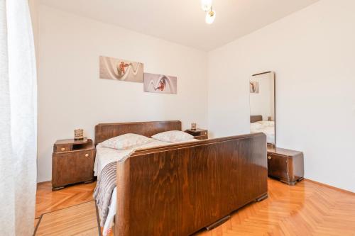Schlafzimmer mit einem Holzbett und einem Spiegel in der Unterkunft Apartment Marinsko in Veli Iž