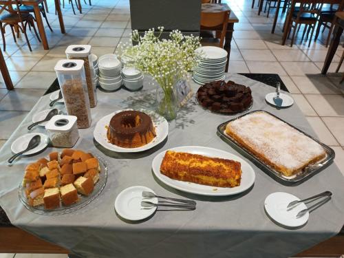 ein Tisch mit verschiedenen Kuchen und Desserts in der Unterkunft Ilha flat Hotel Suíte Swaenen II in Ilhabela