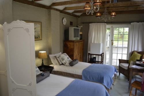 1 dormitorio con 2 camas y TV. en A Garden Suite B&B, en Pietermaritzburg