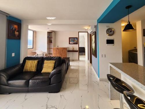a living room with a black couch and a kitchen at 1909 Luxury Cerca Clínica Foscal & Ardila Lulle in Floridablanca