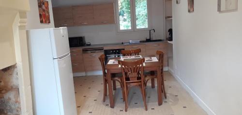 une cuisine avec une table, des chaises et un réfrigérateur dans l'établissement Gîte du Château des Bretonnières sur Vie, à Commequiers