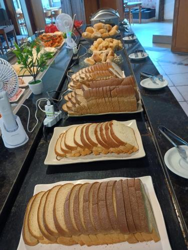 ein Buffet mit belegten Brötchen auf Tellern auf einem Tisch in der Unterkunft Ilha flat hotel suíte Swaenen in Ilhabela