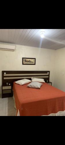a bedroom with a bed with red sheets and pillows at Pousada da vila in Abelardo Luz
