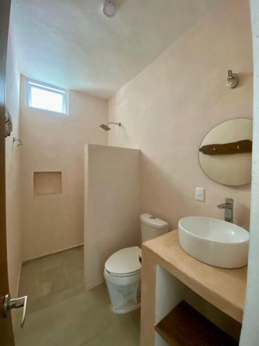 a bathroom with a sink and a toilet and a mirror at Habitat in Barra de Navidad