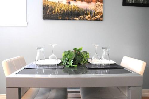 Una mesa de comedor con dos vasos y una planta encima. en Logis des prodiges - Le 775, en Rouyn