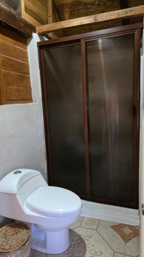 a bathroom with a toilet and a sliding glass door at bacalar My Love Front Laguna in Bacalar
