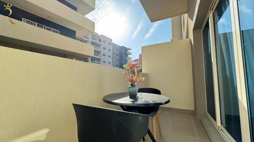 a small table with a vase of flowers on a balcony at Peaceful Al Reef Studio - King Bed Comfort for 2 Near Community Park in Abu Dhabi