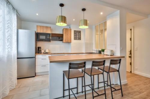 La cuisine est équipée d'un comptoir avec tabourets et d'un réfrigérateur. dans l'établissement Superbe appartement aux portes de Paris WIFI et TV, à Clichy