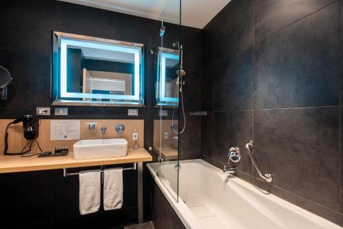 a bathroom with a tub and a sink and a mirror at Novotel Bogota Parque 93 in Bogotá