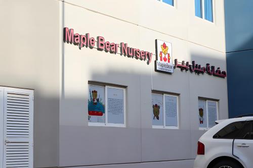 a white building with signs on the side of it at Peaceful Al Reef Studio - King Bed Comfort for 2 Near Community Park in Abu Dhabi