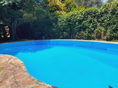 a large blue swimming pool in a yard at Casa quinta con gran parque, pileta y parrilla a 15 min del aeropuerto in La Unión