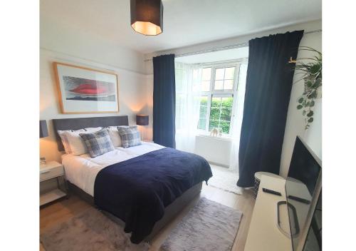 a bedroom with a bed with blue curtains and a window at College House in Crawley
