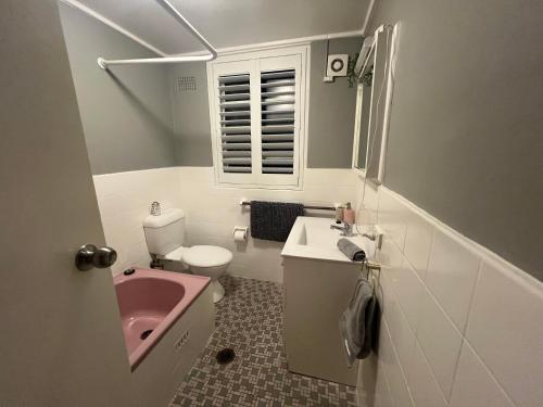 a bathroom with a pink sink and a toilet at Sunny boutique apartment in Sydney