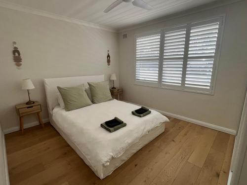 a white bedroom with a bed with a window at Sunny boutique apartment in Sydney