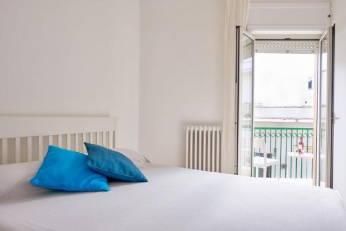 a white bed with two blue pillows on it at Casa Maristella in Otranto