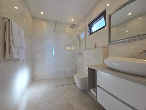 a bathroom with a sink and a toilet and a mirror at Villa Adria Horizon in Bast