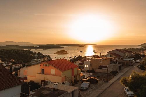a view of a town with the sun setting over the water at Apartments Villa Bella Vista Hvar in Hvar