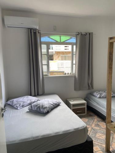 a bedroom with two beds and a window at Pousada Vila do Meio in Pinheiro