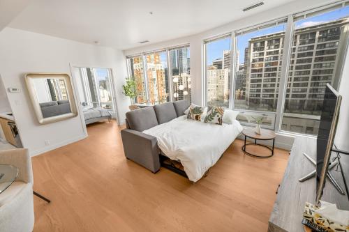 a living room with a bed and large windows at Modern & Cozy Home in the Heart of Downtown Vancouver in Vancouver
