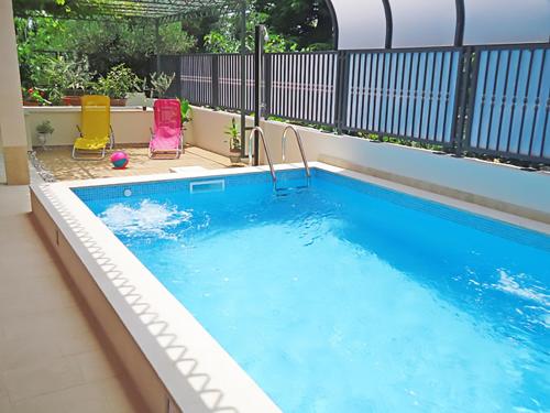 einen Pool mit zwei Gartenstühlen und einem Pool in der Unterkunft Apartment Marjan Park in Split