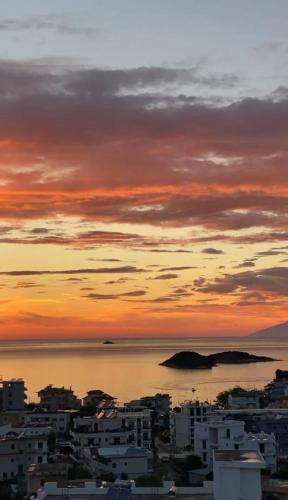 a view of a city with a sunset over the water at NMS Apartments in Ksamil
