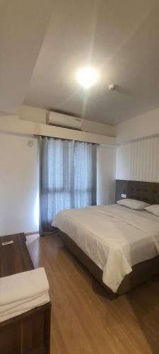 une chambre avec un grand lit et une fenêtre dans l'établissement Cheapest 3 Bedroom Apartment in Sky House BSD - Duxton 1, à Samporo