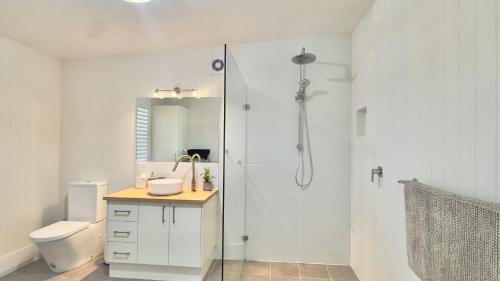 a bathroom with a shower and a toilet and a sink at Jj's Holiday House in Wooli