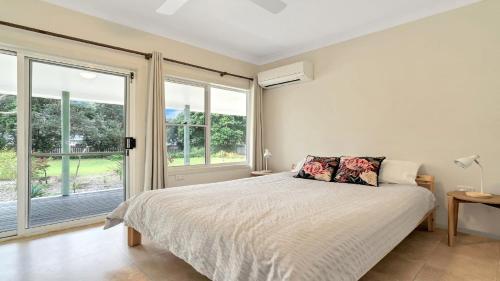 a bedroom with a bed and a large window at Birdsong in Wooli