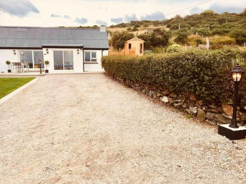 a gravel driveway leading to a white house at Brownes Sea View Cottage No 2 Dungloe 14km in Lettermacaward