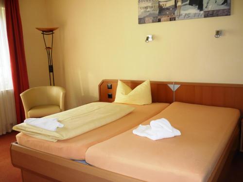 a hotel room with two beds and a chair at Pension Im Malerwinkel Kallmünz in Kallmünz