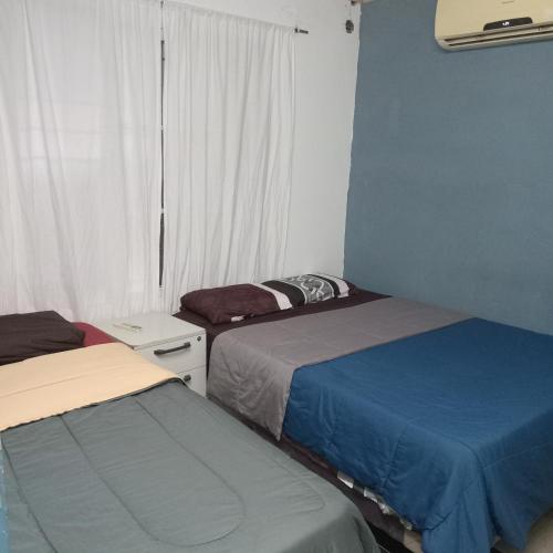 two beds in a small room with a window at Alojamiento B&B Corrientes in Corrientes