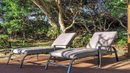 two chairs sitting on a deck with trees in the background at Wooli Waves in Wooli