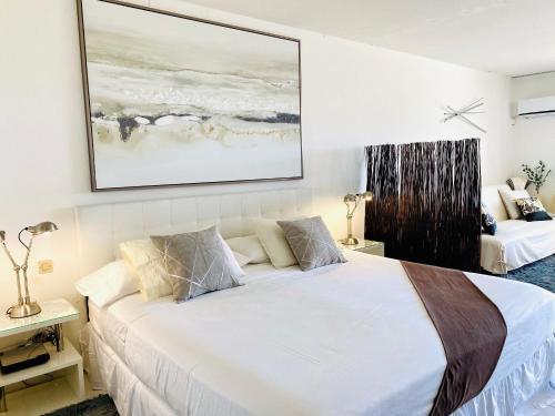 a bedroom with a white bed and a painting on the wall at Excellence Suites Orient Beach Oceanview King-Size Beach Pool Parking in Cul de Sac