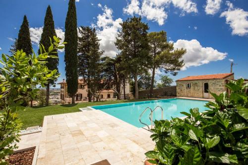 an outdoor swimming pool with trees and a house at Villa Paola 16 in Campiglia Marittima