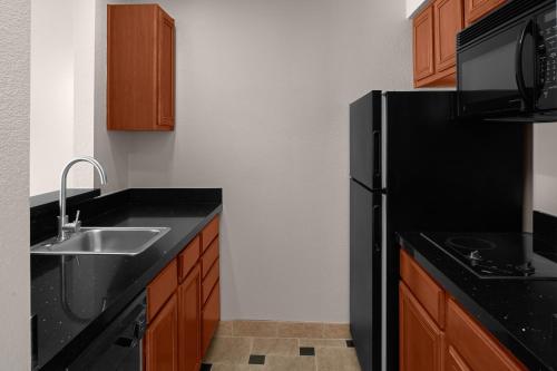 a kitchen with a black refrigerator and a sink at Larkspur Landing Extended Stay Suites Folsom in Folsom