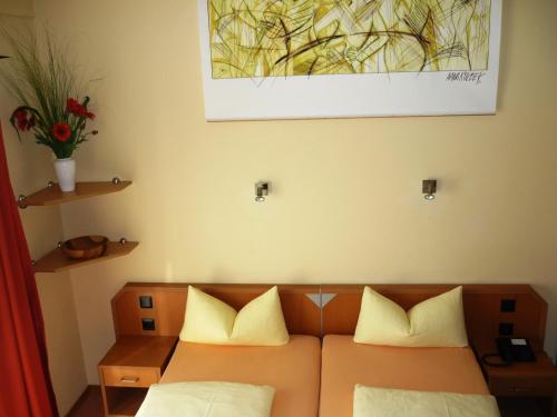 a bed with two pillows and a painting on the wall at Pension Im Malerwinkel Kallmünz in Kallmünz