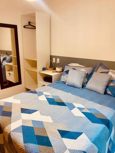 a bedroom with a blue and white bed and a mirror at Chalé Sertão e Mar in Canguaretama