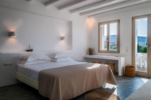 a white bedroom with a large bed and a window at Milia Gi Suites in Pollonia