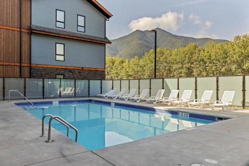 a swimming pool with chairs and a house at 2 bedrooms-3 beds 2 baths-Rocky Creekside Retreat - Top Floor - Heated Pool and Hot Tub in Dead Man's Flats