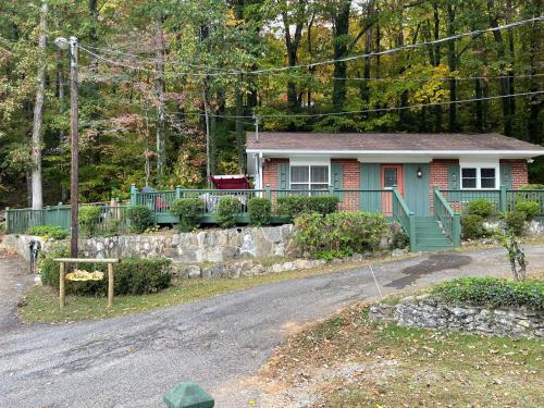 a small house with a green fence and a driveway at Mountain Aire Cottages, Inn, & Glamping in Clayton